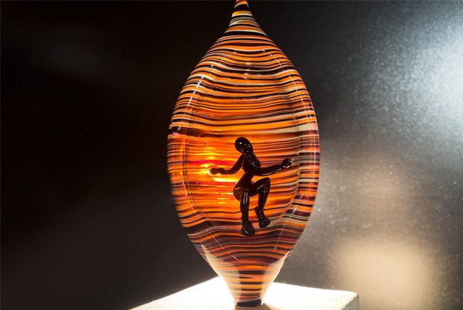 Décoration artisanale d'une sculpture en verre, représentant un personnage surfant sur des vagues de lumière